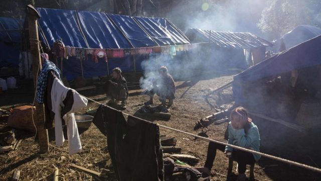 This photo is taken on January 21, 2017 shows refugees in front of their temporary shelter near Lung Byeng village, Waimaw township in Kachin state