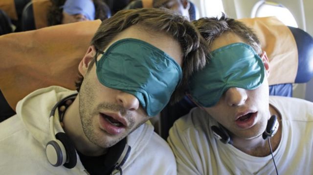 Passageiros de avião dormindo com proteção nos olhos