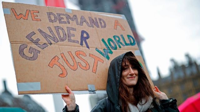 Une femme porte une pancarte "nous demondons un monde juste pour tous les genres"