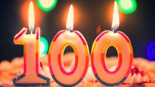 Velas de aniversário acesas formando o número 100
