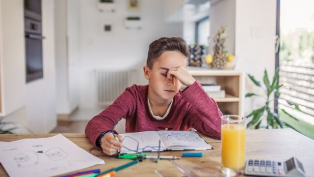 Menino demonstrando frustração ao estudar