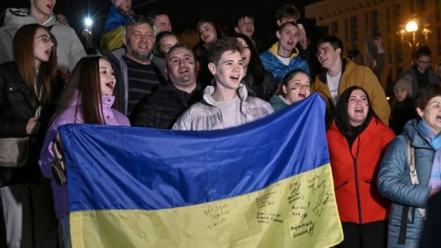 Warga Ukraina mengibarkan bendera mereka di Lapangan Kemerdekaan di Kyiv.