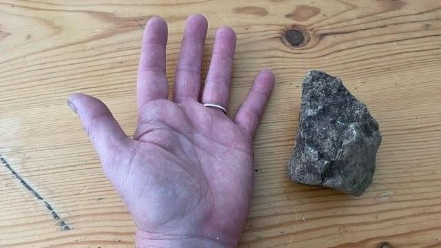 A picture of a person's hand compared to the rocks that were thrown. 