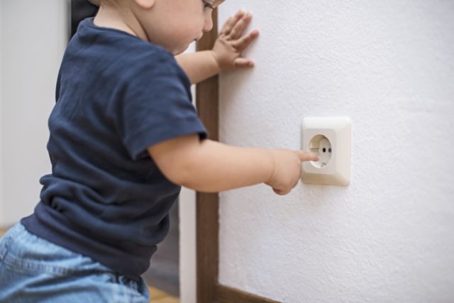 Bebê colocando dedo na tomada