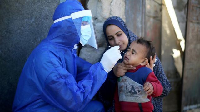 A Palestinian medical worker performs a coronavirus test for a child