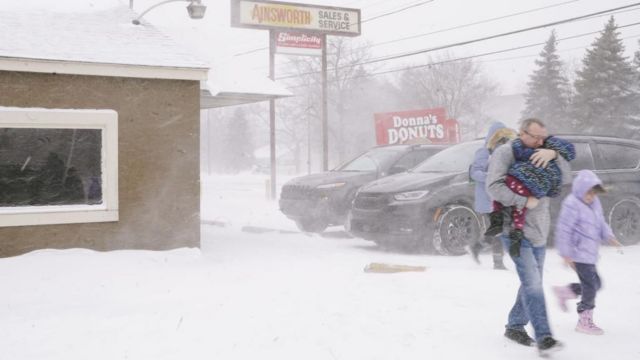 Một gia đình di chuyển nhanh ra xe hơi nhằm tránh cái lạnh ở Flint, Michigan hôm 23/12