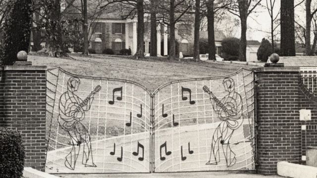 Foto en blanco y negro de la reja, curvada y con dos figuras a ambos lados similares al rey del rock, con guitarra, pantalones acampanados y tupé y varias notas musicales en grande alrededor.