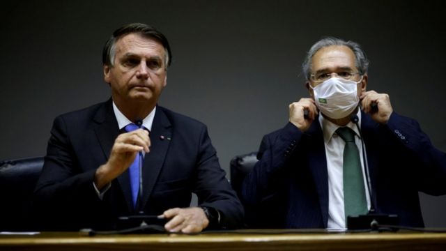 Bolsonaro e Guedes sentados, em entrevista coletiva