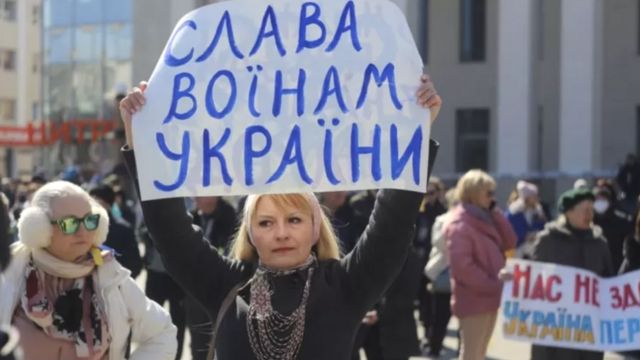 Herson'daki Rusya karşıtı protestoda bir kadın "Ukrayna savaşçılarına zafer" yazan pankart taşıyor.