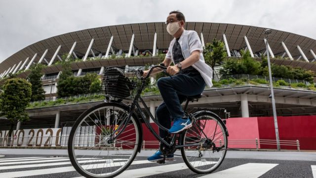 Um homem anda de bicicleta pelo estádio olímpico