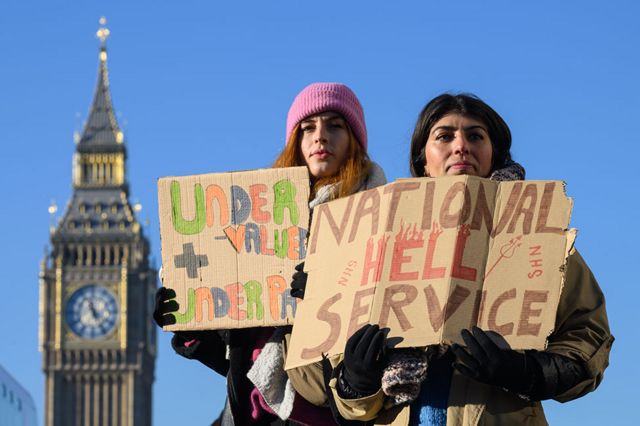 ممرضات ومؤيديين يحملون لافتات وهم يتظاهرون خارج مستشفى سانت توماس في وستمنستر، لندن.
