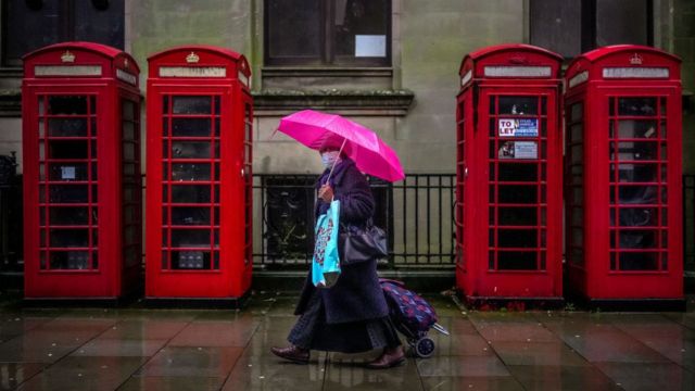 Una mujer con mascarilla camina por una calle en Inglaterra.