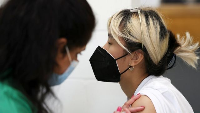 A woman wearing a face covering while she is vaccinated