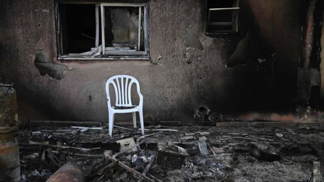 被烧毁的房子外有一把塑料椅子