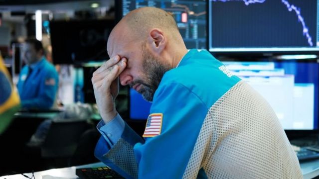Funcionário de bolsa americana lamentando cenário de queda de ações