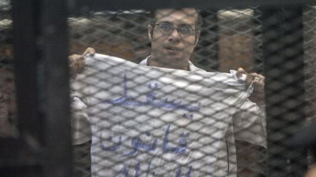 أحمد ماهر خلف القضبان، يحمل قميص كُتب عليه "يسقط قانون التظاهر"