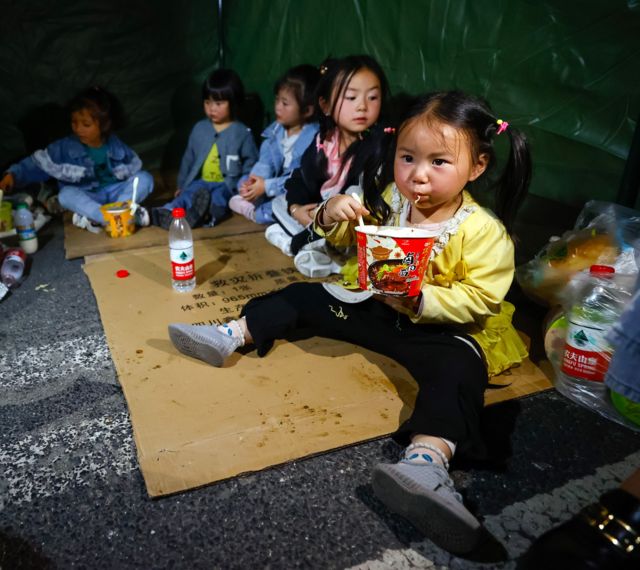 9月5日晚，在四川甘孜州泸定县磨西镇的受灾群众临时安置点，几个家庭的孩子们在一个帐篷里吃饭、休息。