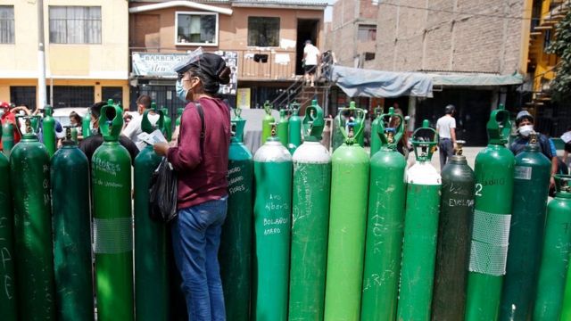 A woman waits for an oxygen cylinder to be recharged at a private supplier in Peru's capital Lima