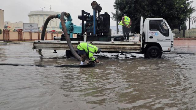 عامل بلدية يحاول نزح مياه الأمطار من الشارع