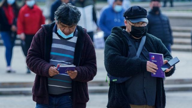 Dos hombres caminan por Santiago de Chile con ejemplares de la nueva Constitución en sus manos
