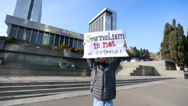 Əlində plakat tutan jurnalist