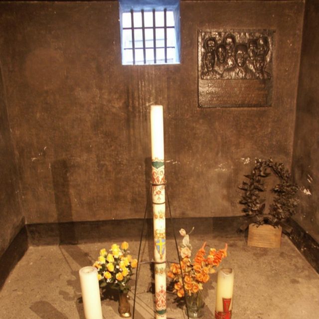 cela de Kolbe em Auschwitz, com pequena janela e velas