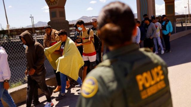 Migrantes pasan por delante de una agente de la patrulla fronteriza en El Paso, Texas
