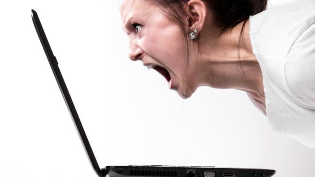 Mujer estresada gritando a la computadora