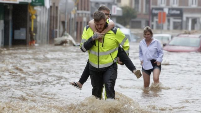 People walk through flooded streets after heavy rain in Insevale, Verviers, Belgium.