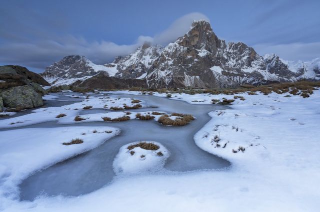 A frozen pond with mountains behind