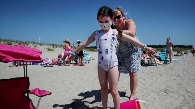 Uma banhista ajuda a filha a passar protetor solar em Good Harbor Beach em Gloucester, Massachusetts