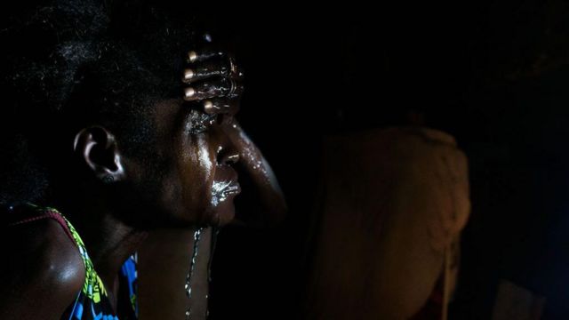 Moradora de favela do Rio de Janeiro lavando o rosto durante onda de calor extremo em dezembro de 2023