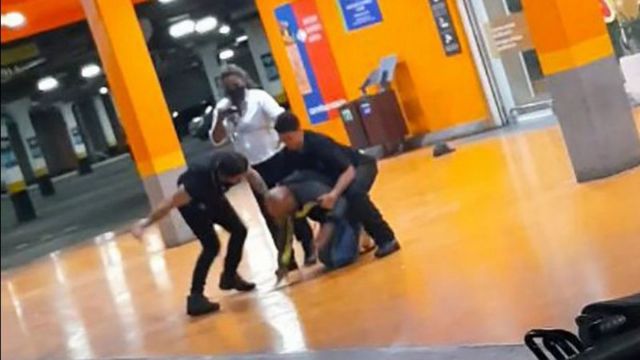 Imagem de agressão no Carrefour, com três funcionários ao redor de homem