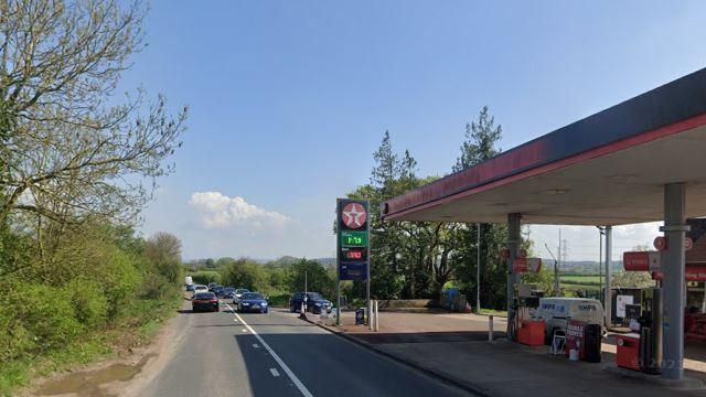 Cars travelling up and down the B4215 near a Texaco petrol station on a sunny day