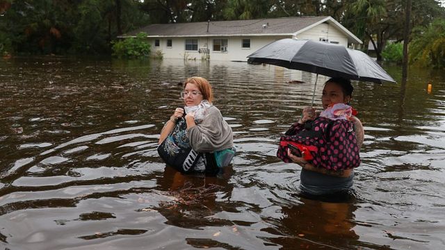 Una joven y su madre caminan por una calle inundada con el agua hasta la cintura