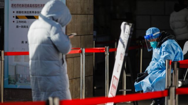 Um profissional de saúde voluntário senta-se em frente à clínica para pacientes com covid no hospital de Chaoyang, em Pequim