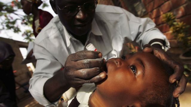 Niño al que un médico le suministra la vacuna oral de la polio.