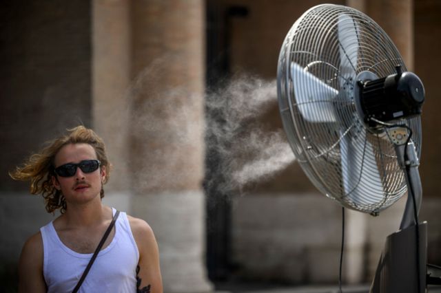 رجل يقف أمام مروحة خلال موجة الحر المستمرة مع درجات حرارة تصل إلى 44 درجة ، في منطقة الكولوسيوم، في 17 يوليو/ تموز 2023 في روما، إيطاليا.