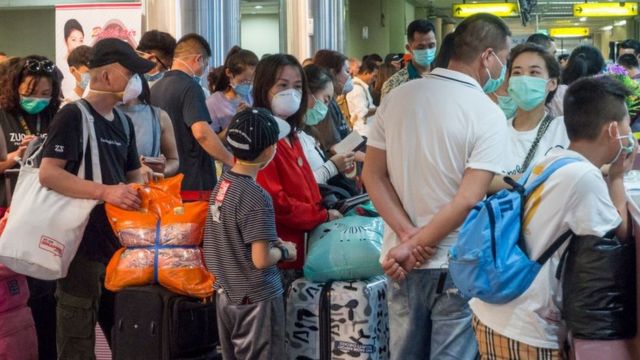 Une foule masquée se rassemble au comptoir d'enregistrement d'un aéroport en Chine