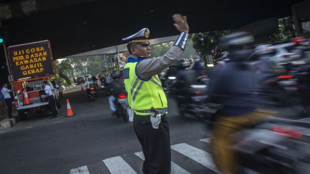 Polisi mengatur arus lalu lintas pada hari pertama uji coba perluasan kawasan ganjil genap di persimpangan Pancoran, Jakarta, Senin (2/7).