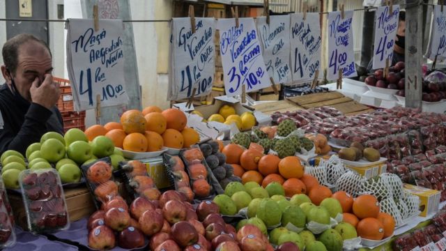 Cartazes de preços em barraca de frutas numa feira livre