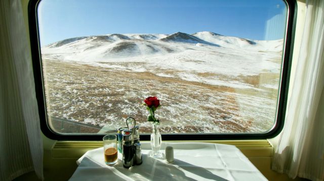 Mesa de almoço em frente a janela, de onde se ve morro nevado