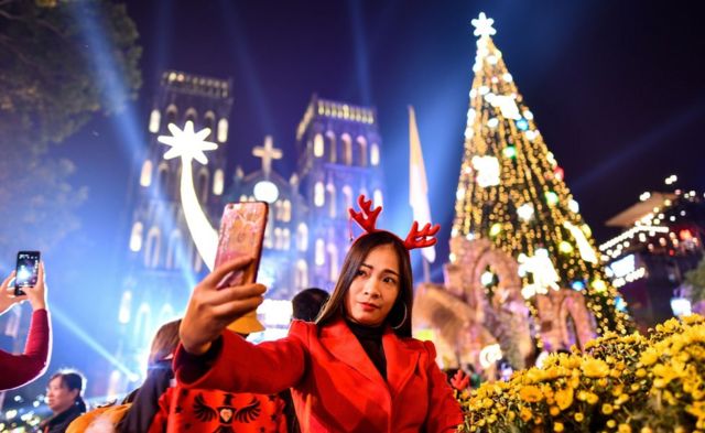 A woman takes a selfie outside . Joseph"s cathedral in Hanoi on December 24, 2019.