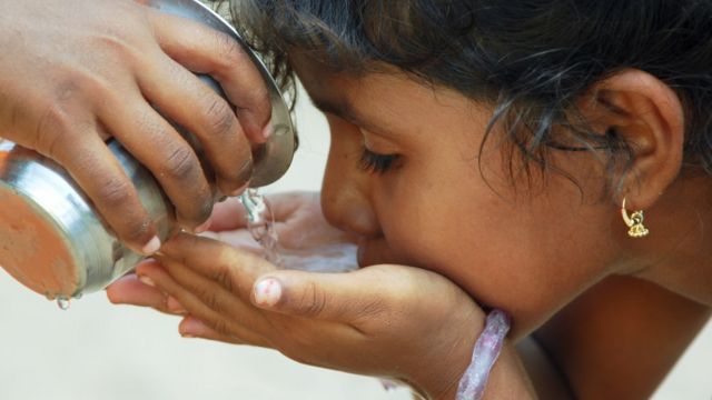 Niña pequeña en India tomando agua