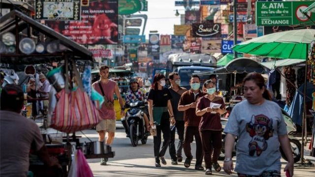 People wear facemasks amid concerns over the spread of the COVID-19 novel coronavirus while walking along Khao San Road