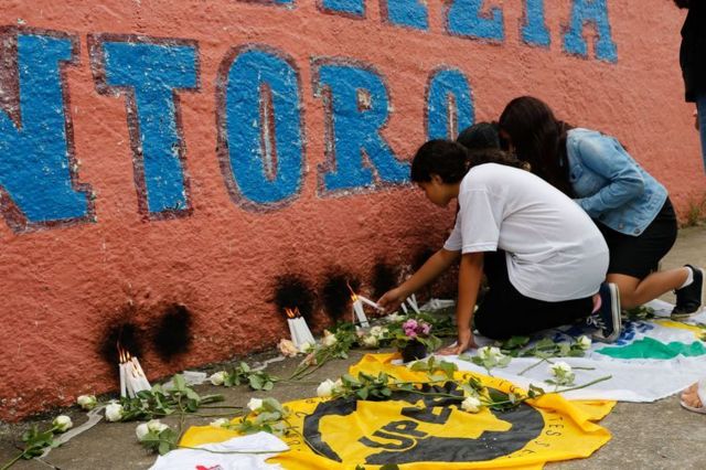 Pessoas colocando flores em frente a fachada de escola alvo de ataque em São Paulo