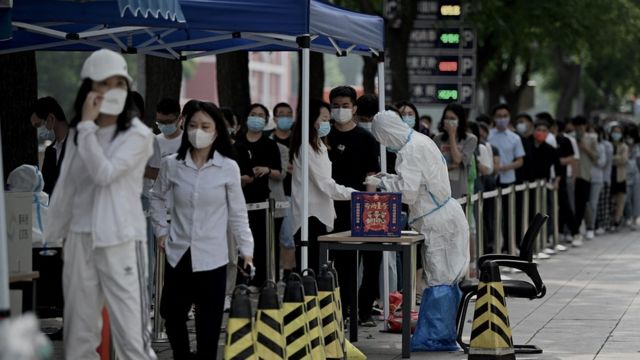 La gente hace cola en un lugar de recogida de hisopos para realizar la prueba del coronavirus en Pekín