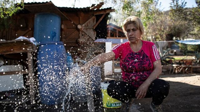 Luz Valdebenito abre un grifo después de que un camión cisterna le distribuyera agua en Til Til, Chile.