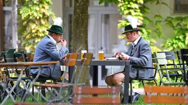 Homens com veste típica da Baviera comendo e tomando cerveja