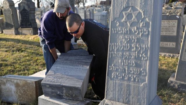 Scott Shandler (L) and Jon Lattanzio re-set a tombstone